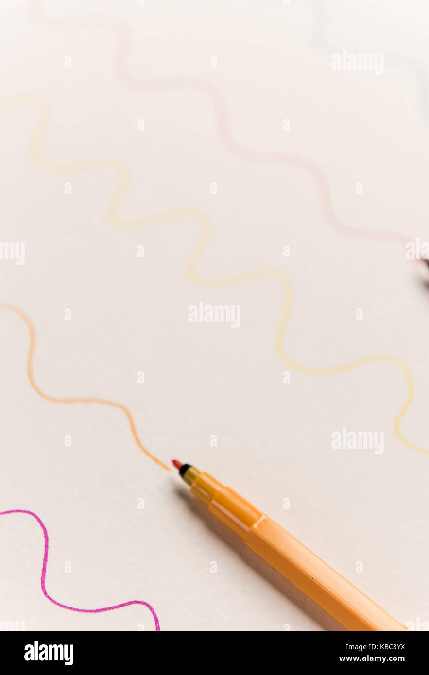 Close up of orange highlighter painting wavy line on white paper. Lines for logo, text Stock