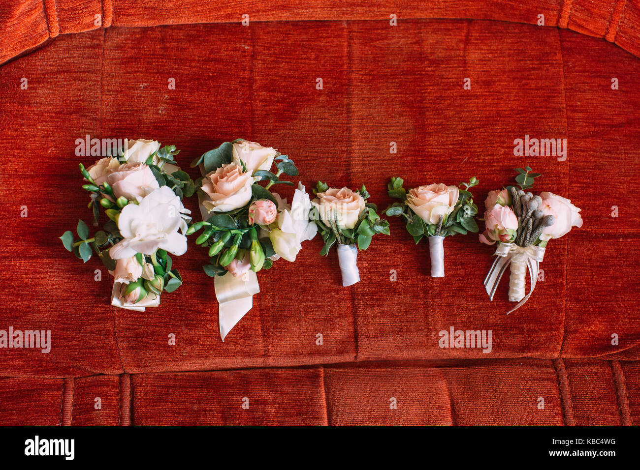 Wedding set of five boutonnieres of white roses on the red background