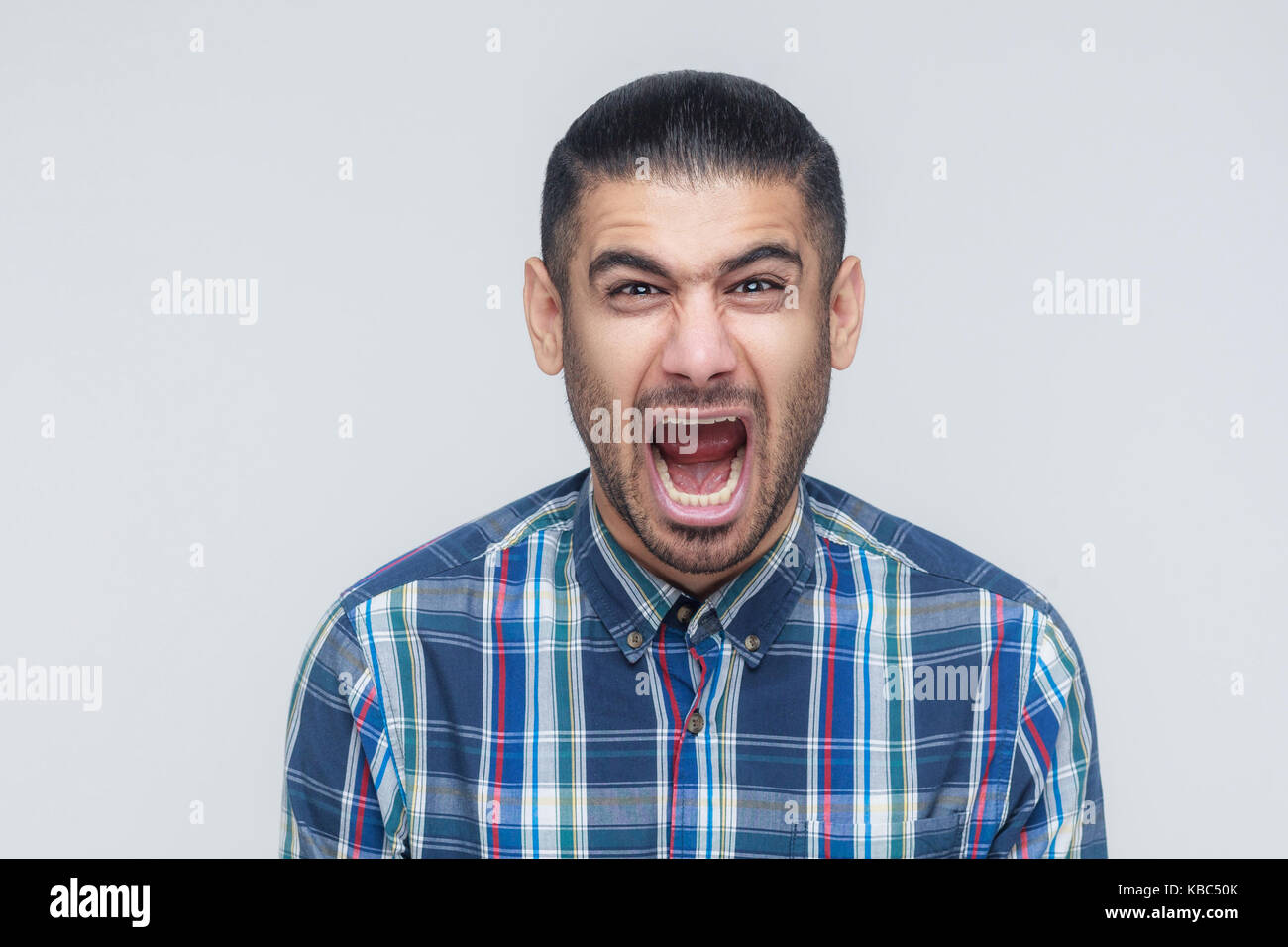 Mans roar! The angry businessman, screaming with closed eyes. Indoor, studio shot.  Gray background Stock Photo