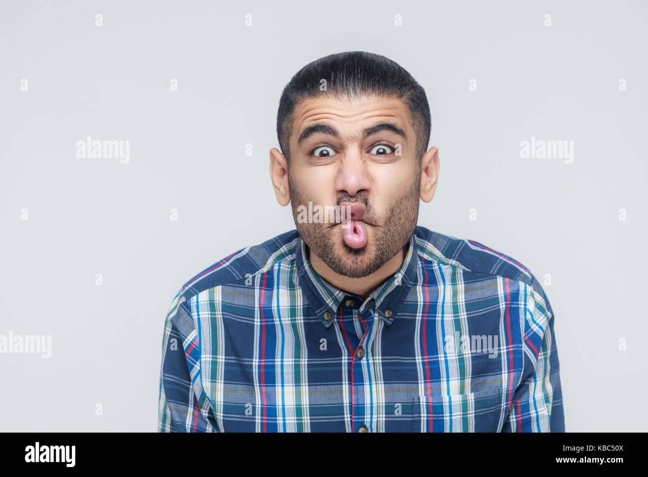 comic faces concept. Funny hipster showing stupid face and looking at camera. Studio shot Stock Photo