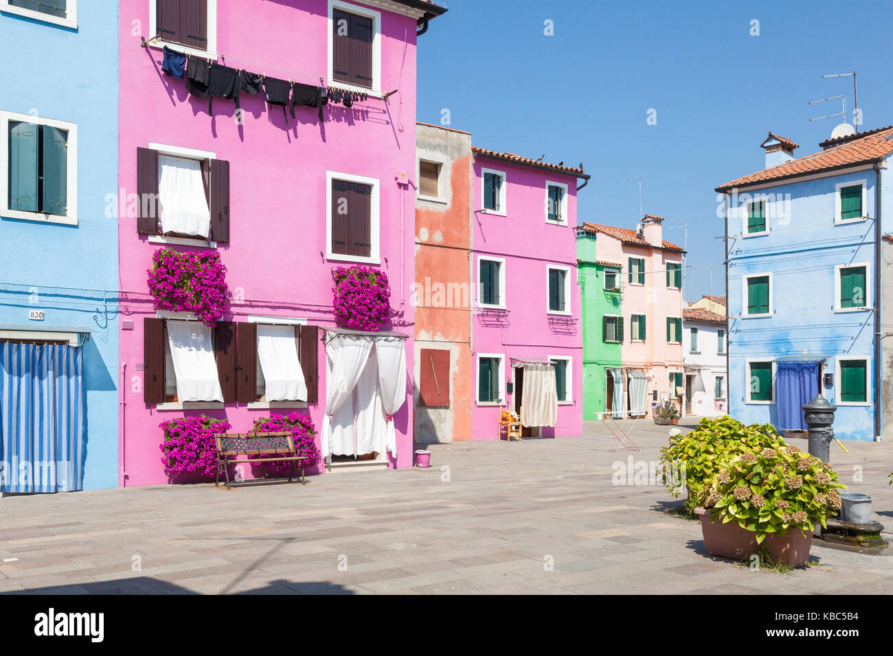 Burano, Venice, Veneto, Italy colorful square in the fishing village with bright houses decked in summer flowers and a water fountain Stock Photo