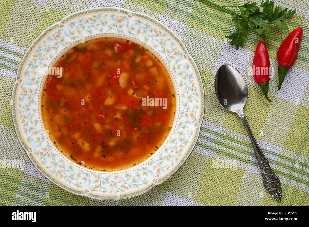 Homemade delicious traditional bulgarian bean soup (bob chorba) with pepper, tomatoes, onion and spices, served with red chili peppers Stock Photo