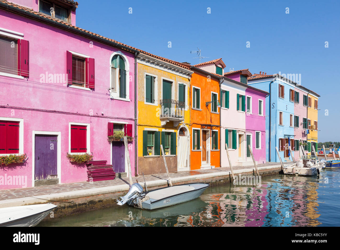 Row of bright colorful houses Burano, Venice, Veneto,  Italy reflected in the canal in early morning light. Stock Photo