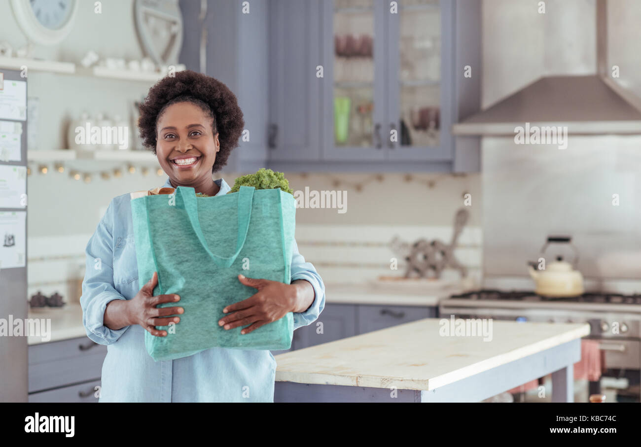 Smiling African woman standing at home with a shopping bag Stock Photo