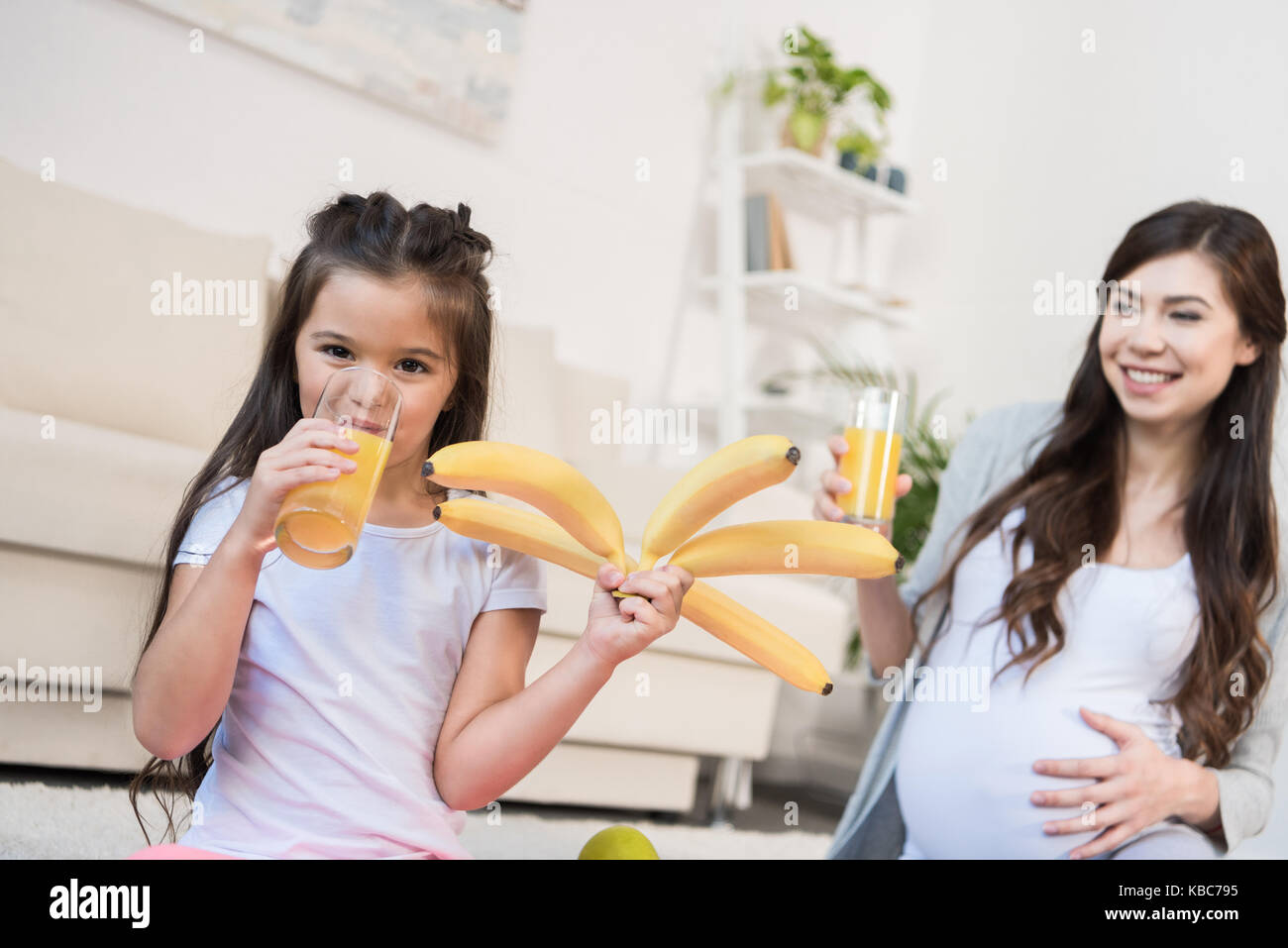 Girl holding bananas and drinking juice Stock Photo