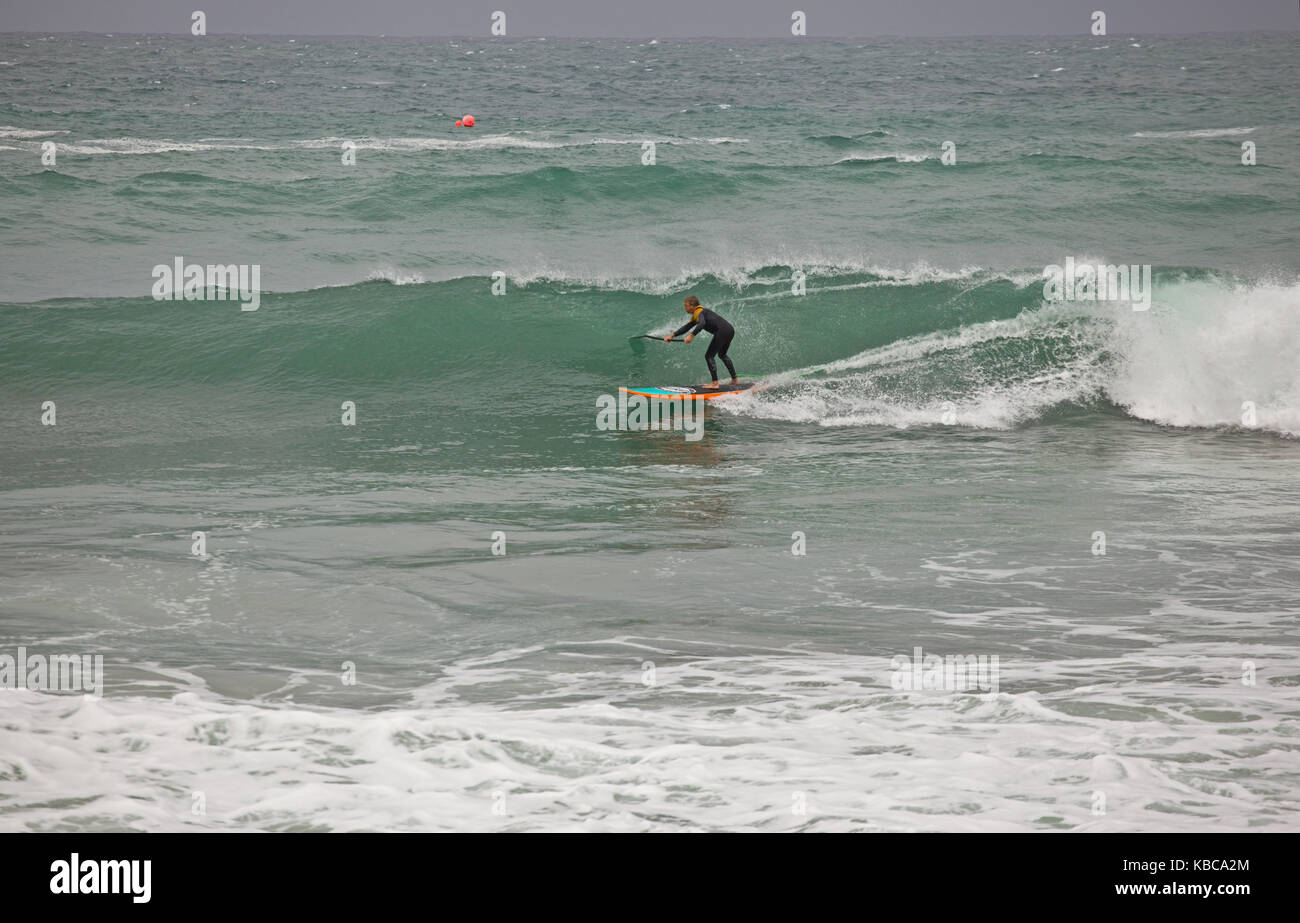 Stand up Paddleboard SUP rider riding a wave at Trevaunance Cove, St ...