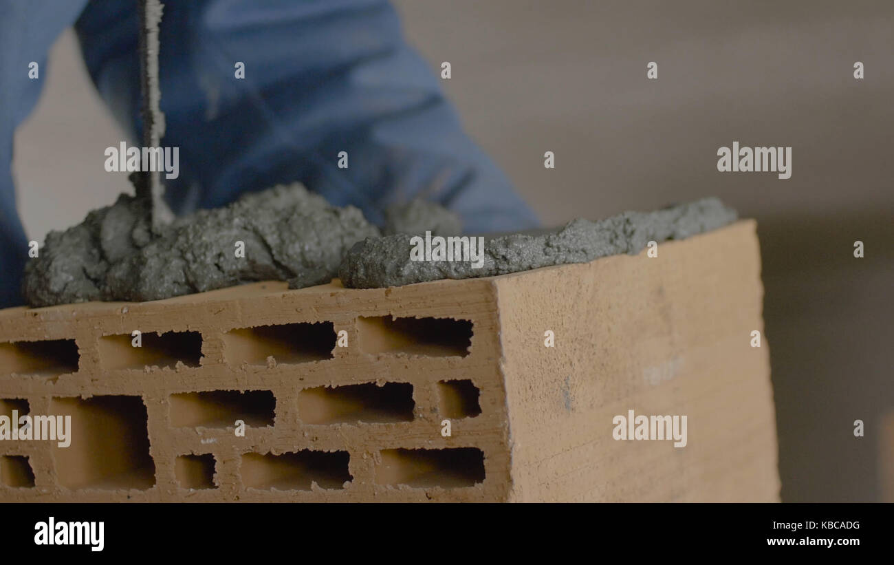 Construction of brick wall. Trowel spreading cement on bricks. Worker