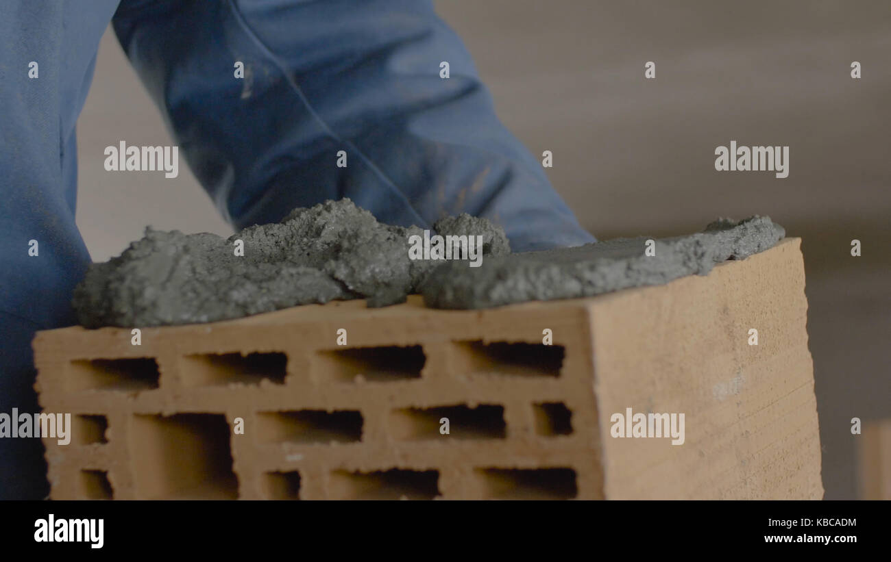 Construction of brick wall. Trowel spreading cement on bricks. Worker