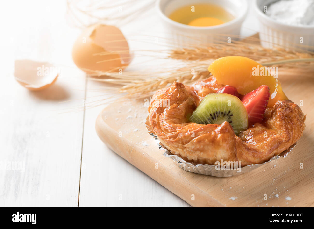 Danish bread with kiwi orange and Strawberry fruits on white wood background, bakery food Stock Photo