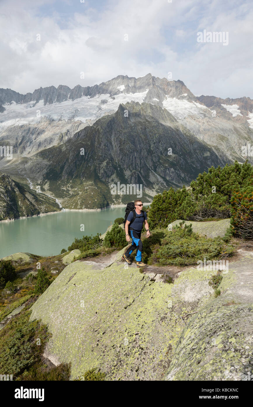 Hiker hikes through a wild high alpine landscape with a lake and ...