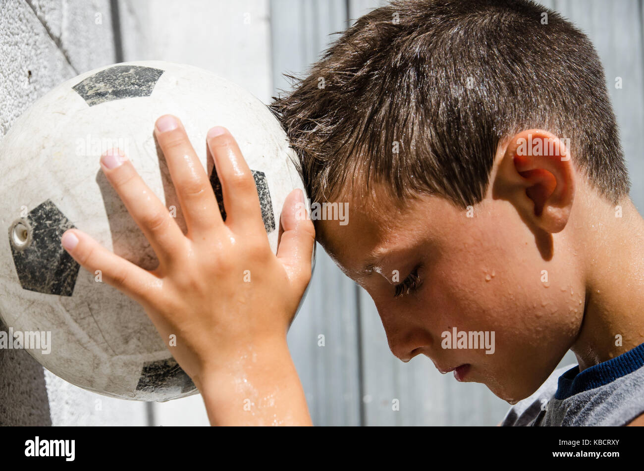 a young sweaty soccer player leans his forehead to the ball. Stock Photo