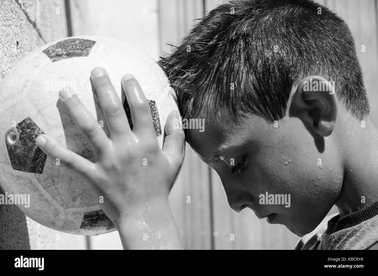 a young sweaty soccer player leans his forehead to the ball. black and white picture Stock Photo
