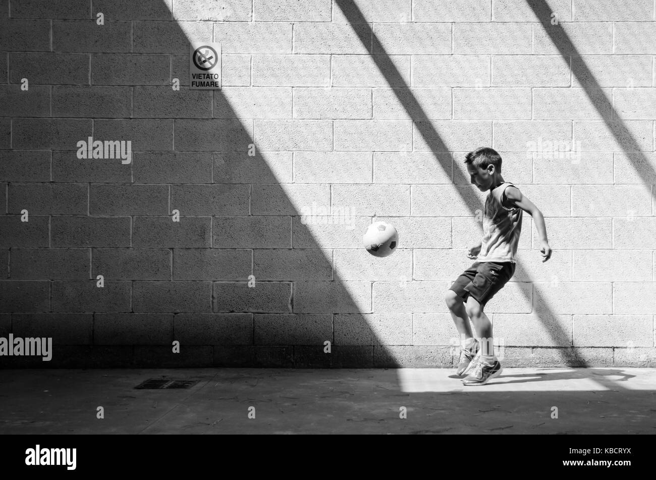 Street football. Young man soccer player. Lonely training in the garage. Black and white picture. Stock Photo