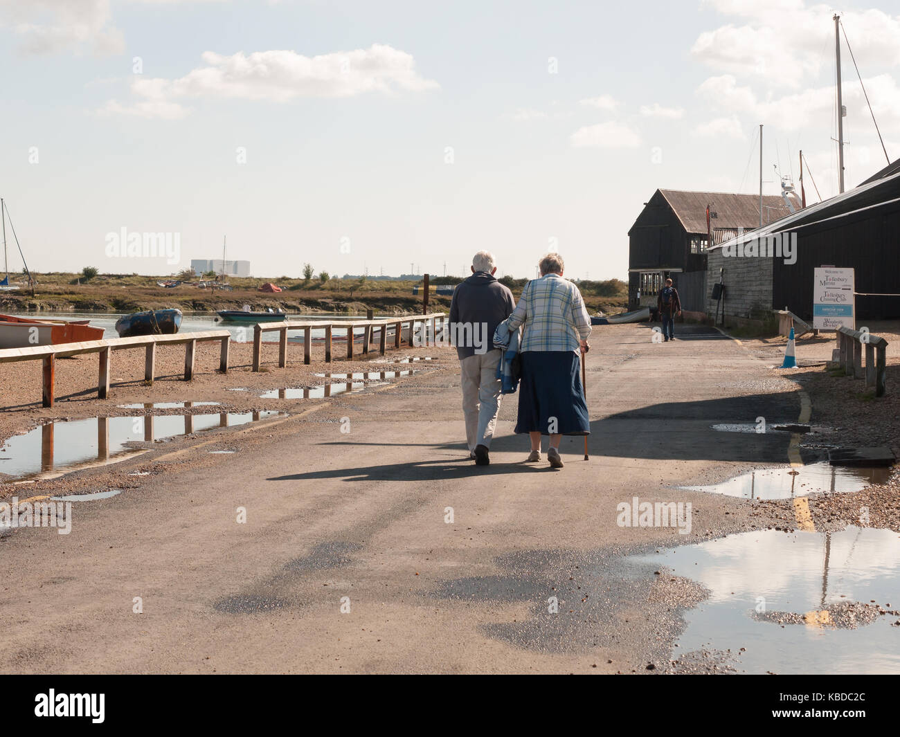 couple of senior old people walking down the dock path holding hands ...