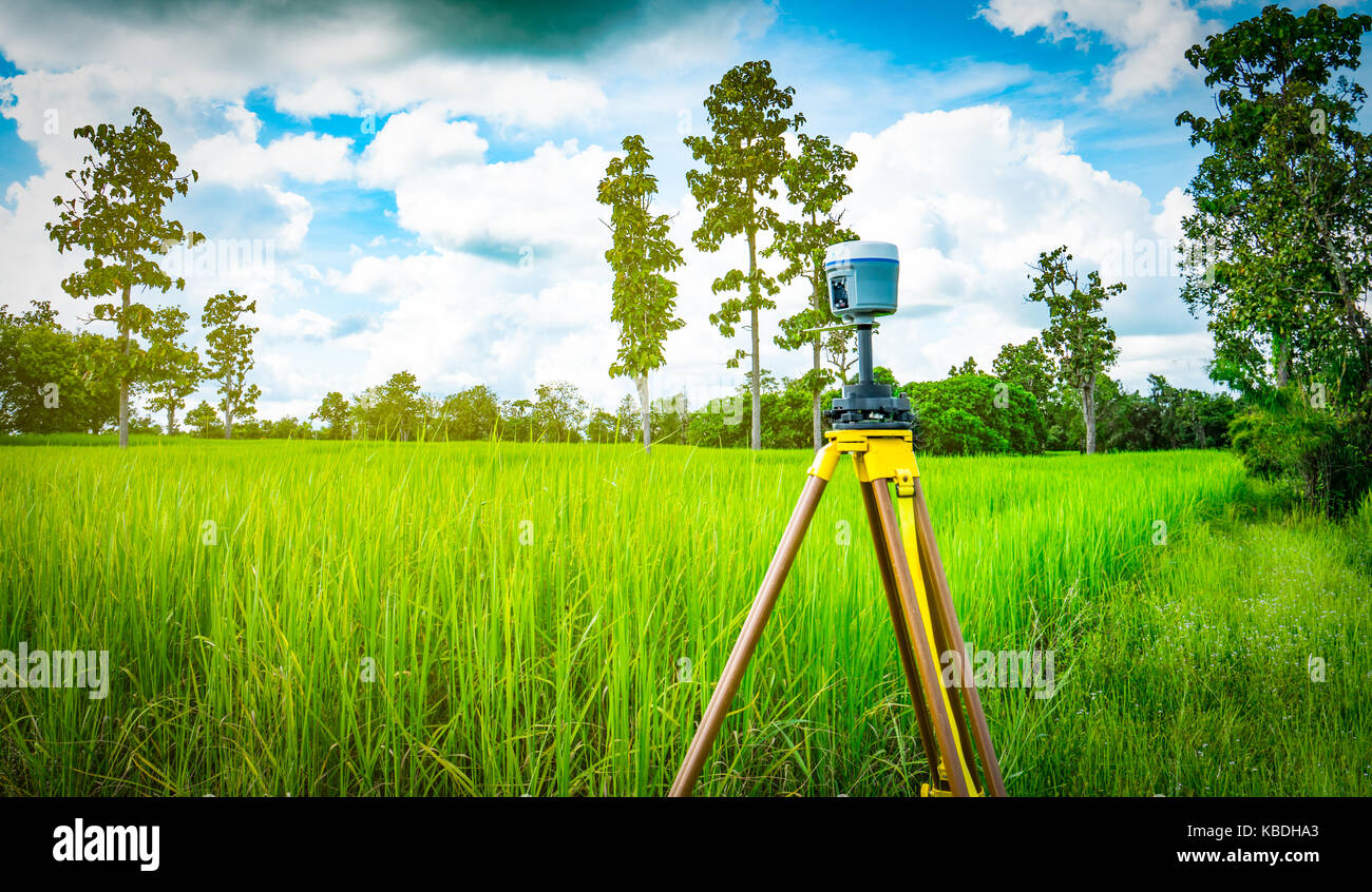 GPS surveying instrument install on tripod in green rice field, Thailand Stock Photo