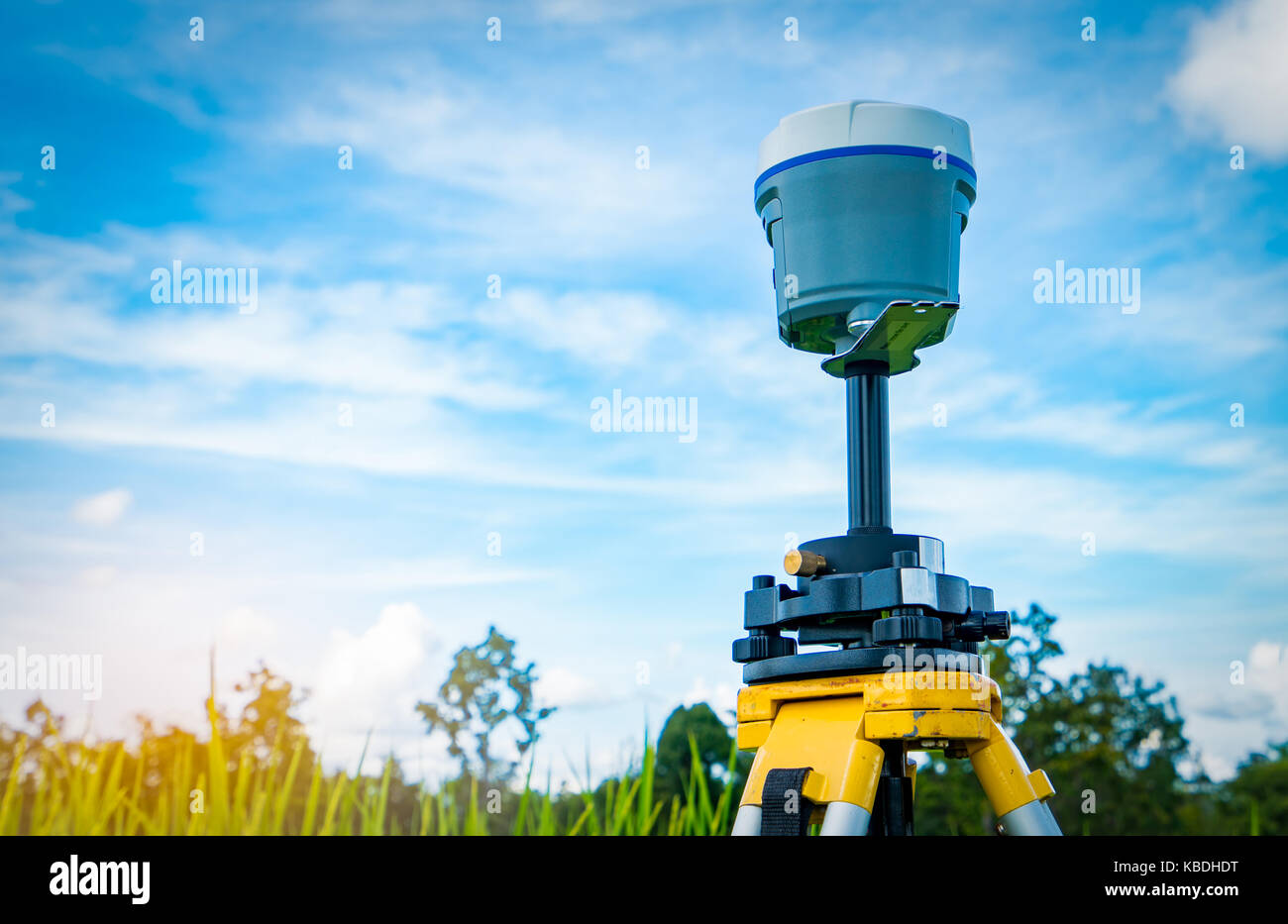 GPS surveying instrument on blue sky and rice field background Stock Photo