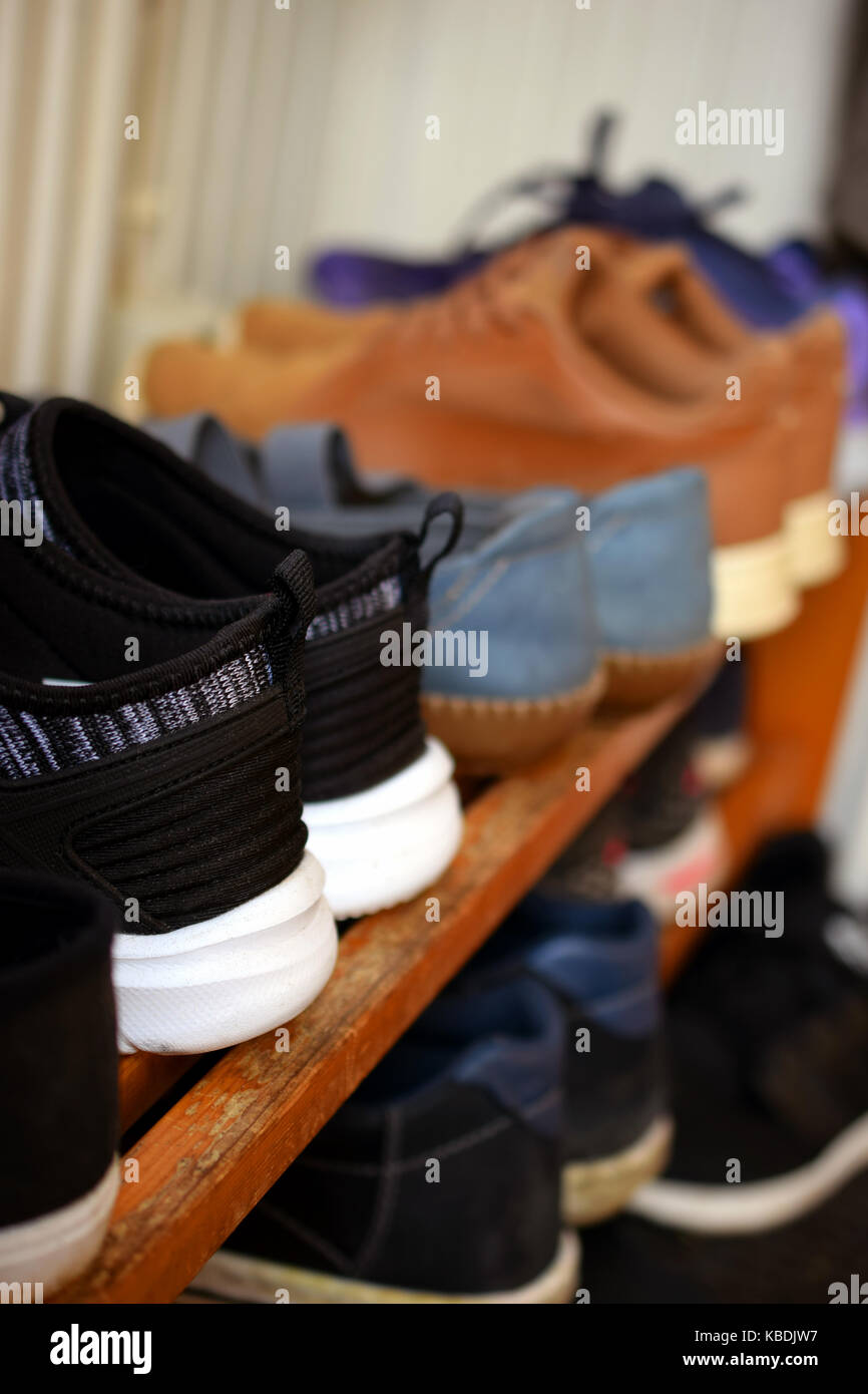 Shoes on wooden shoe rack. Close up side view vertical image. Stock Photo