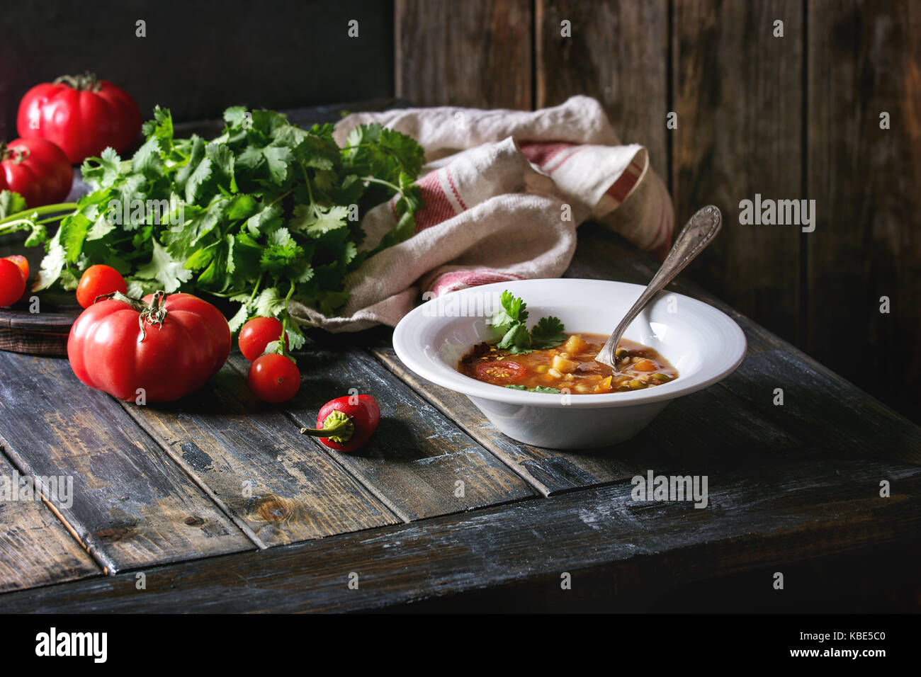 Vegetarian hot carrot tomato pea potato soup, served in plate and vintage aluminum pan with