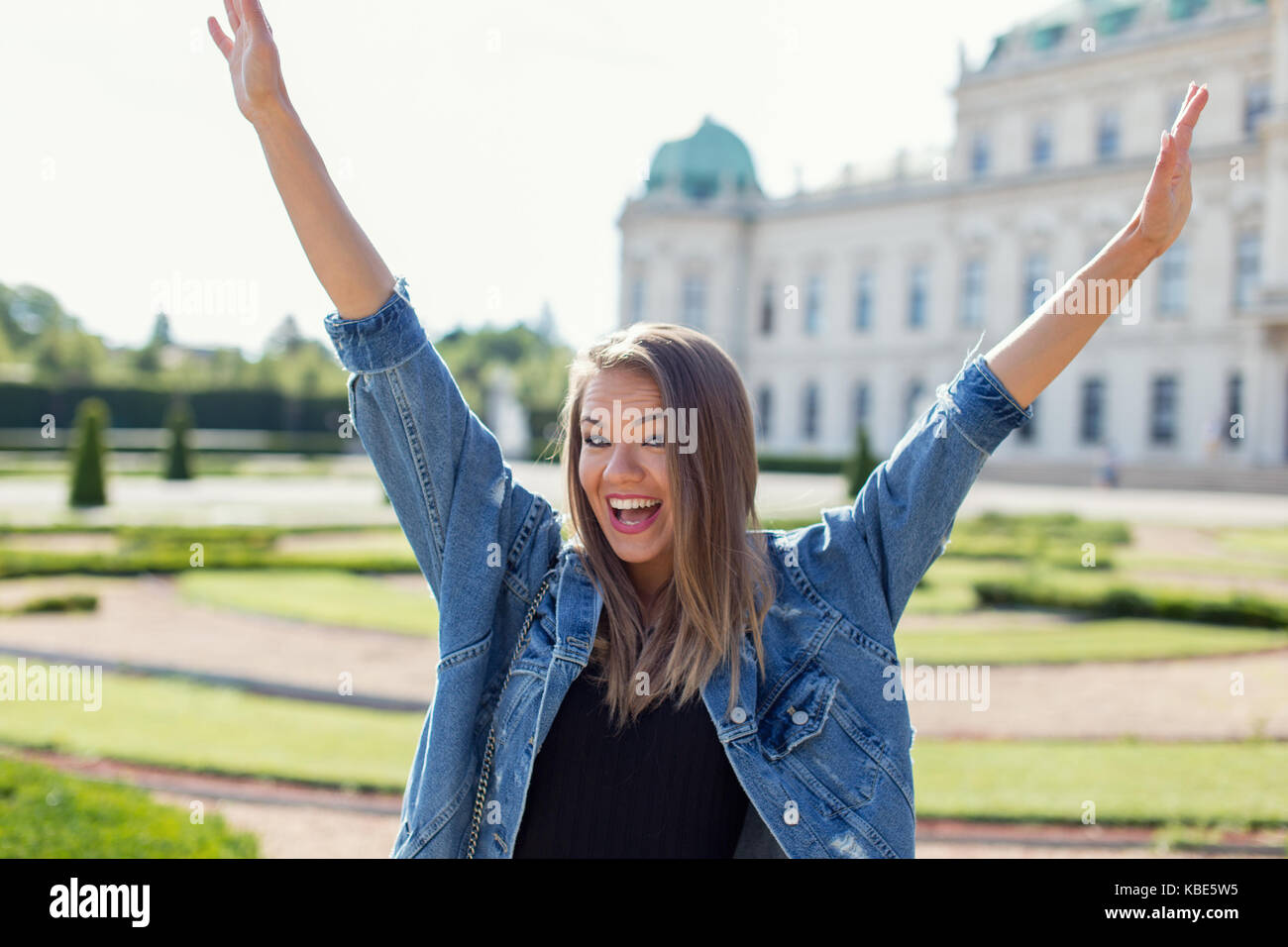 Happy young caucasian casual woman hands up, European architecture, summer holiday Stock Photo