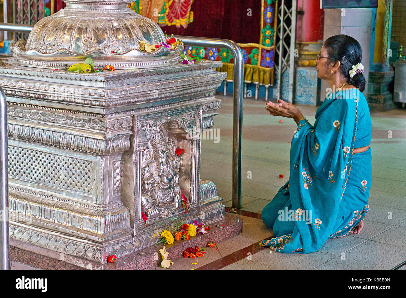 Woman worshipping in Sri Srinivasa Perumal Temple, one of Singapore's oldest Hindu temples, in the heart of Little India where its tall Gopuram show Stock Photo