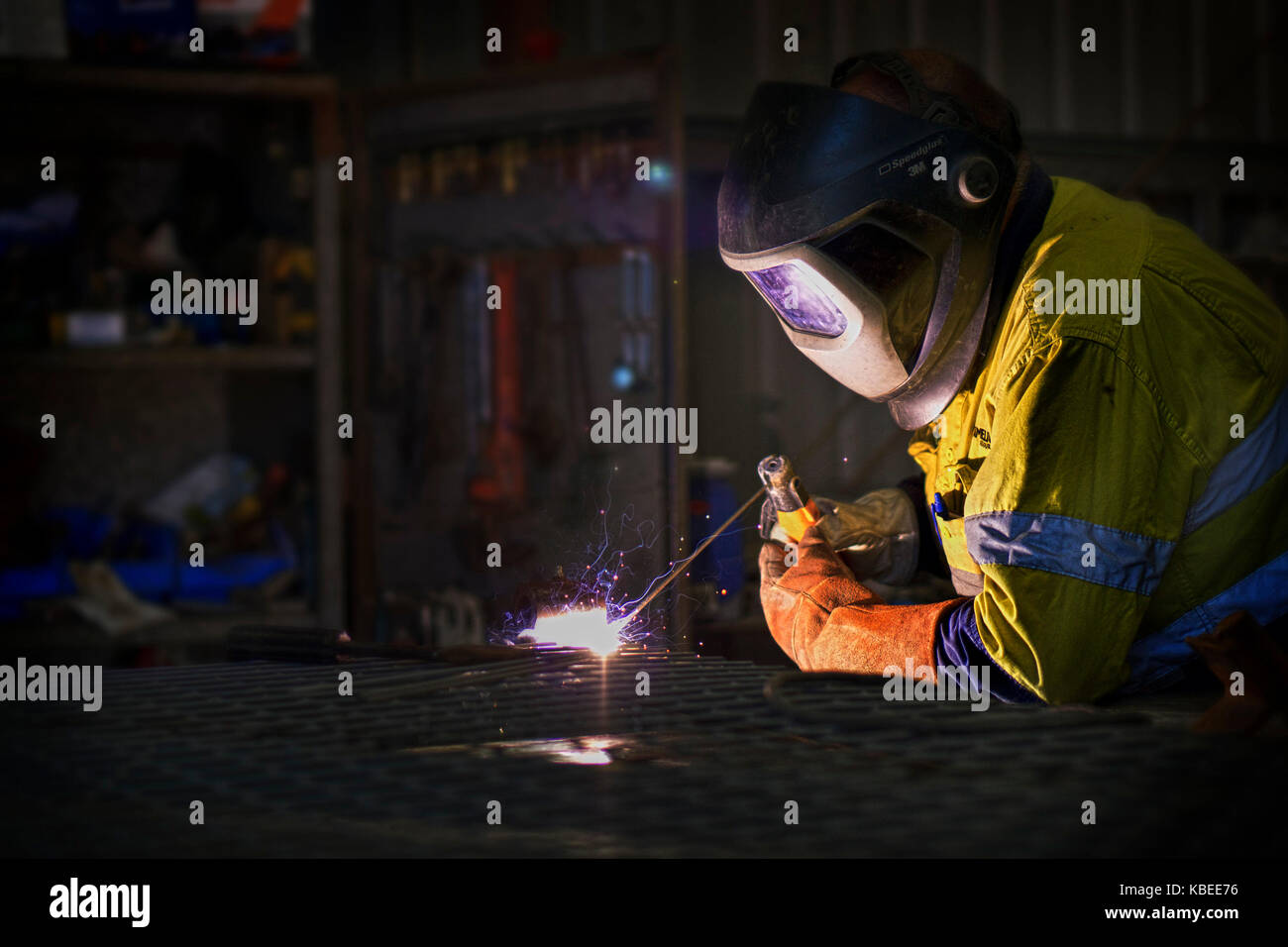 A welder at work clad in protective heavy jacket, gloves and helmet and goggles. Western Australia Stock Photo