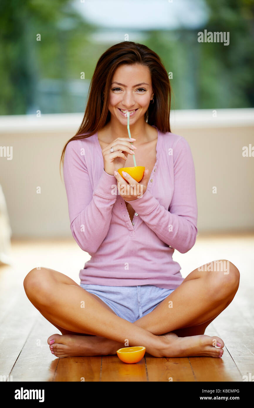 Girl sat holding orange and a straw Stock Photo