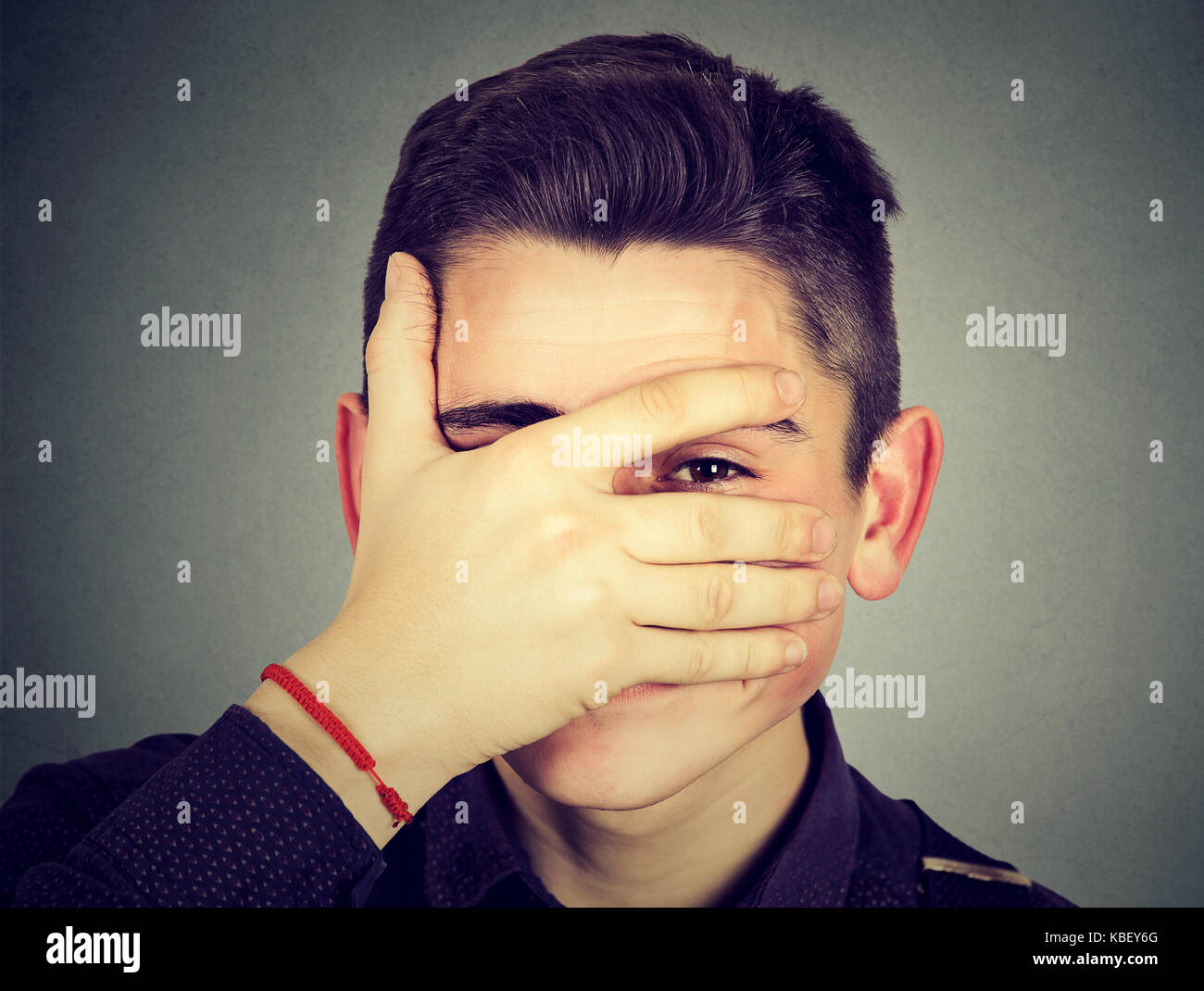 Portrait of a shy man peeking through his fingers Stock Photo