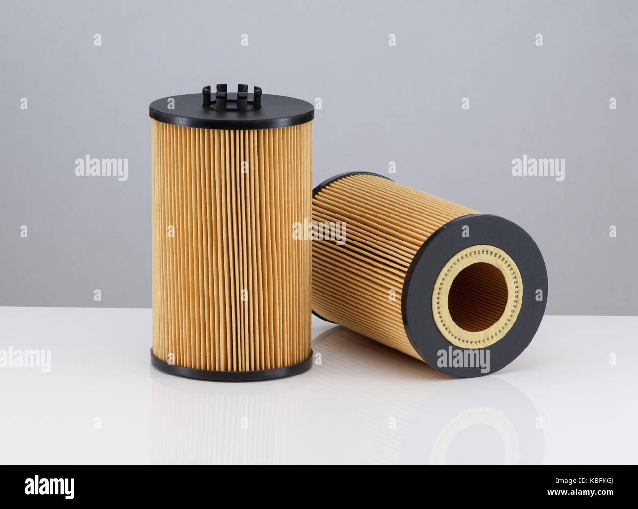 two automotive filter cylindrical shape of orange color on a white ...