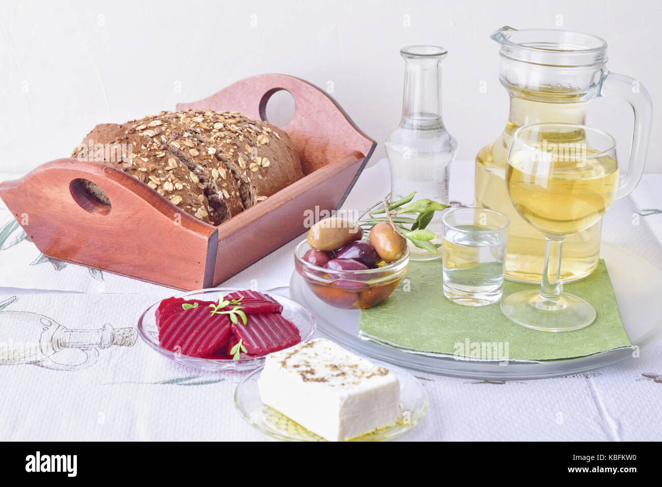 Greek mezedes. Jars with olive oil and vine vinegar, olives,feta, tzatziki, dark bread, raki, beetroot, fresh cucumber and tomato, white background Stock Photo