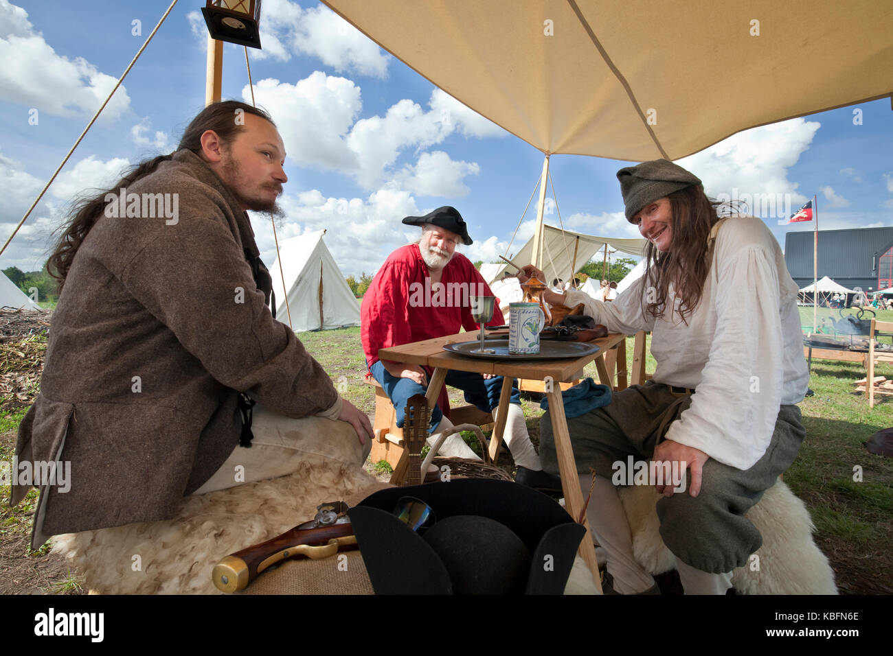 A group of men, 18th century 'smugglers', sitting around a table at living history fayre in Stowmarket, UK. Stock Photo