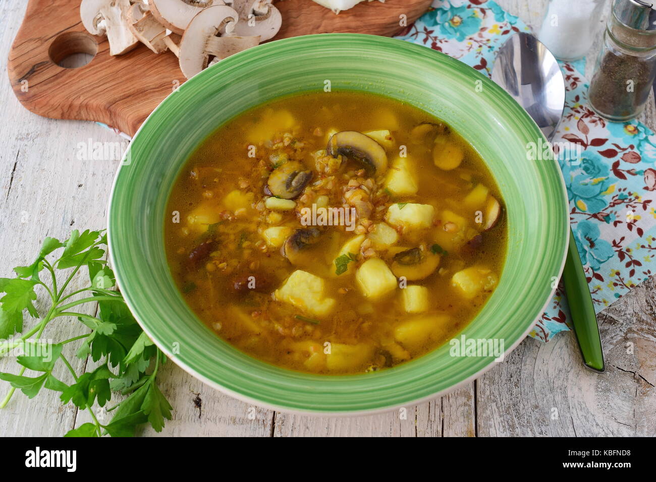 Healthy soup with buckwheat, potato, mushrooms, carrots and onion wit olive oil in a green bowl on a wooden background Stock Photo