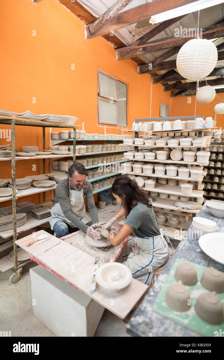 Male potter assisting female potter in pottery workshop Stock Photo - Alamy