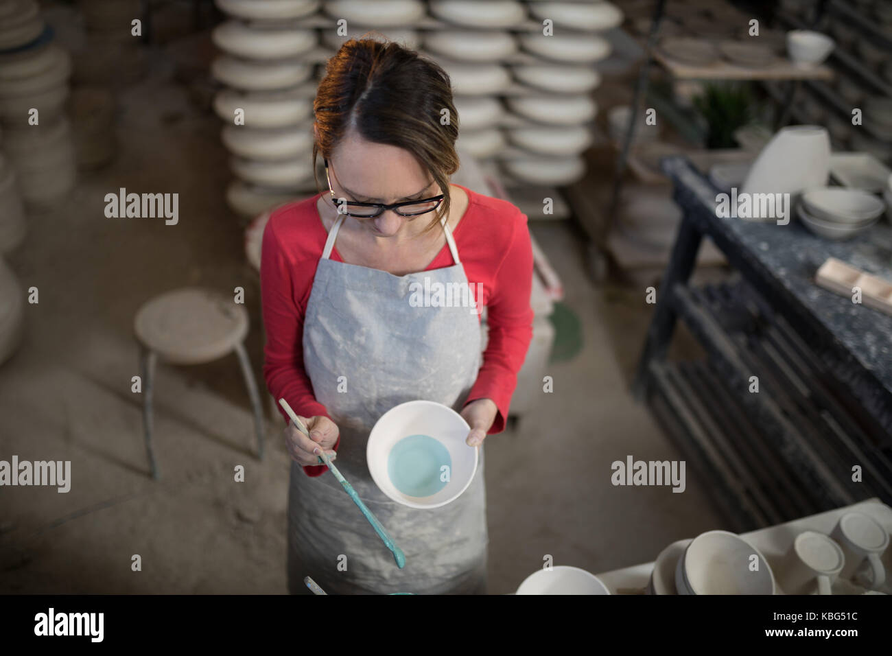 Overhead of female potter painting bowl in pottery workshop Stock Photo ...