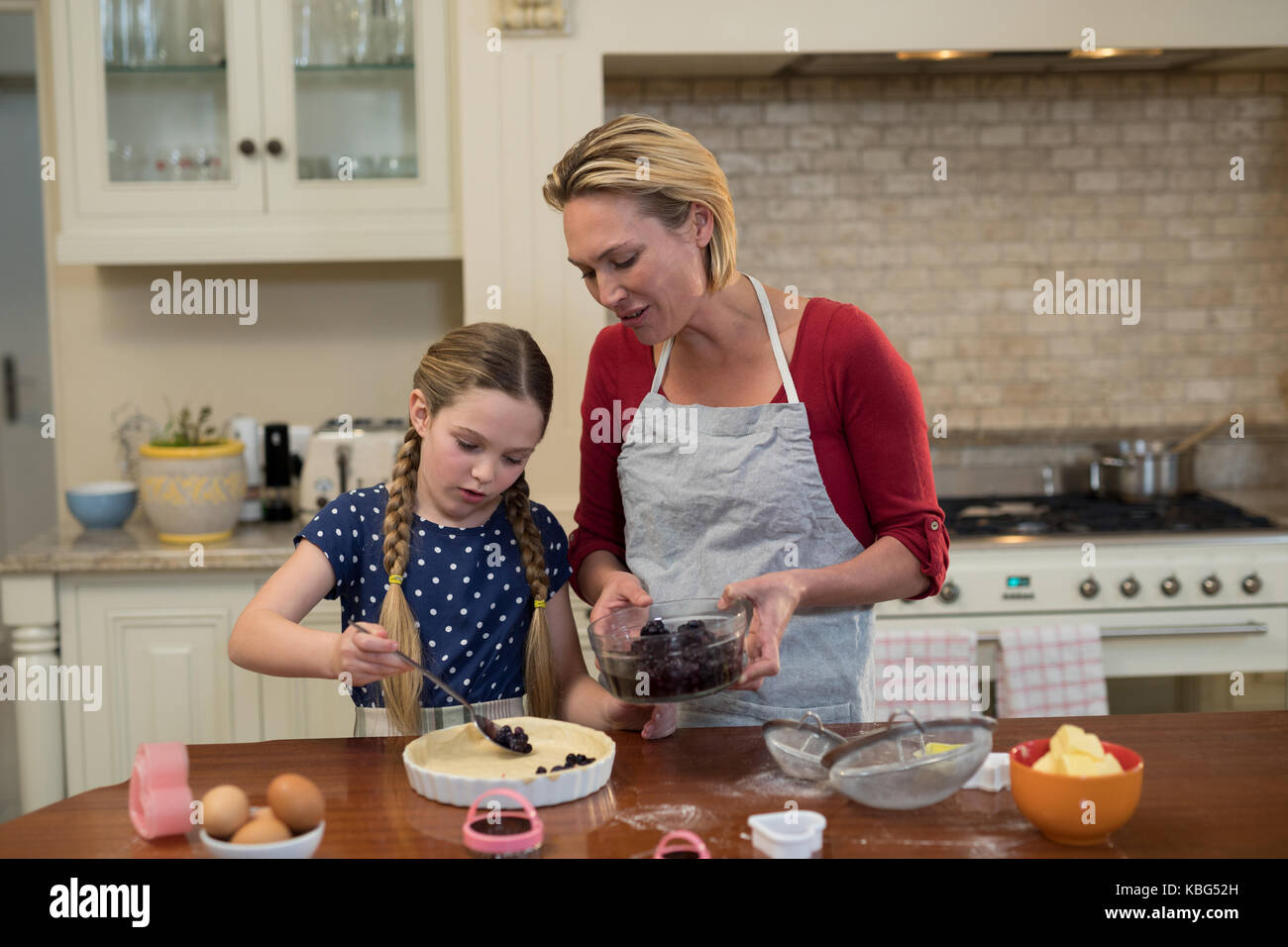 Mother and daughter preparing blue berry pie in kitchen Stock Photo