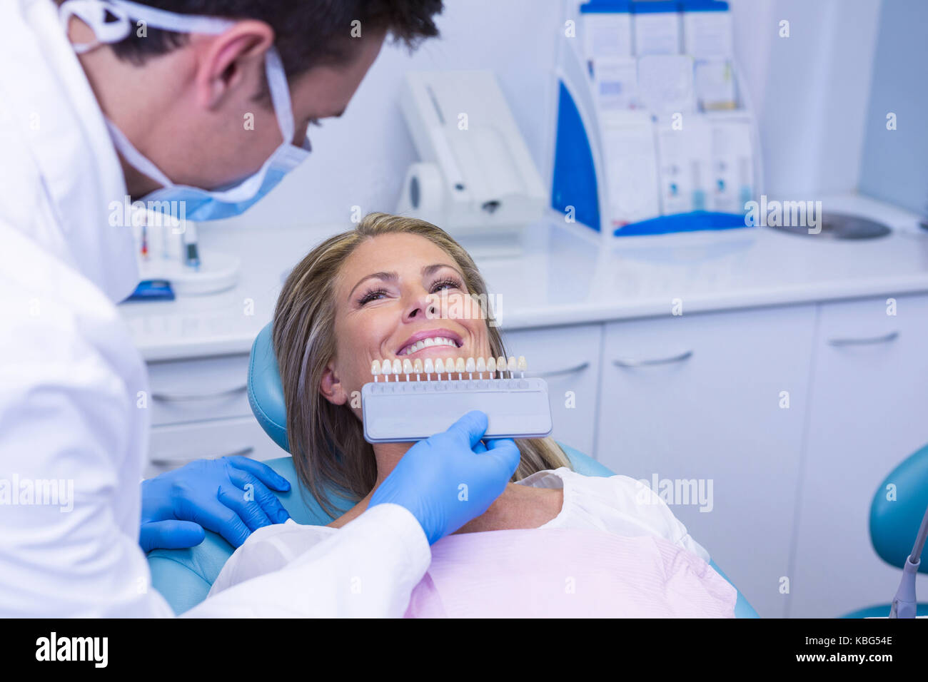 Doctor Holding Tooth Whitening Equipment By Smiling Patient - 
