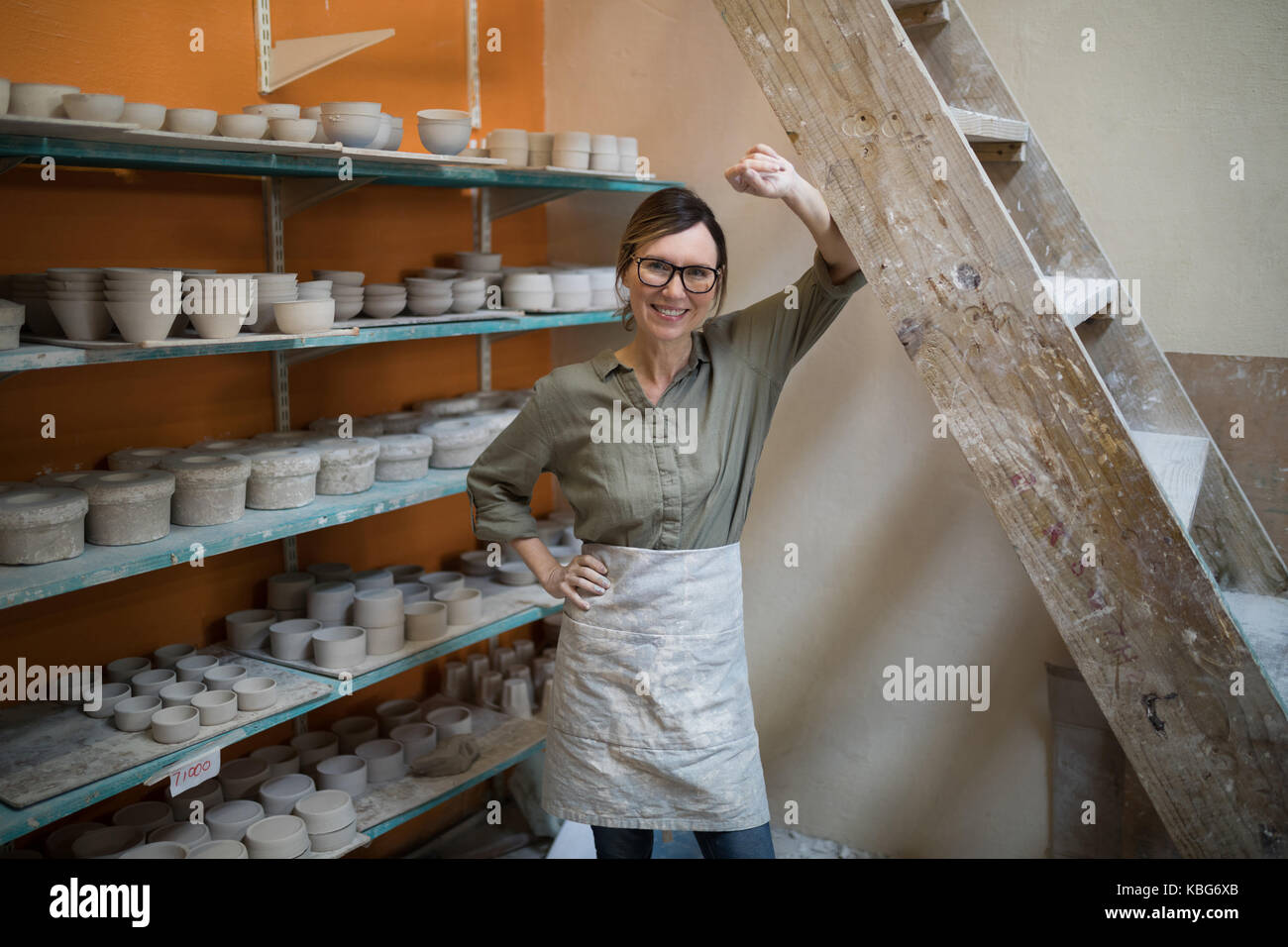 Portrait of female potter standing near shelf in pottery workshop Stock ...