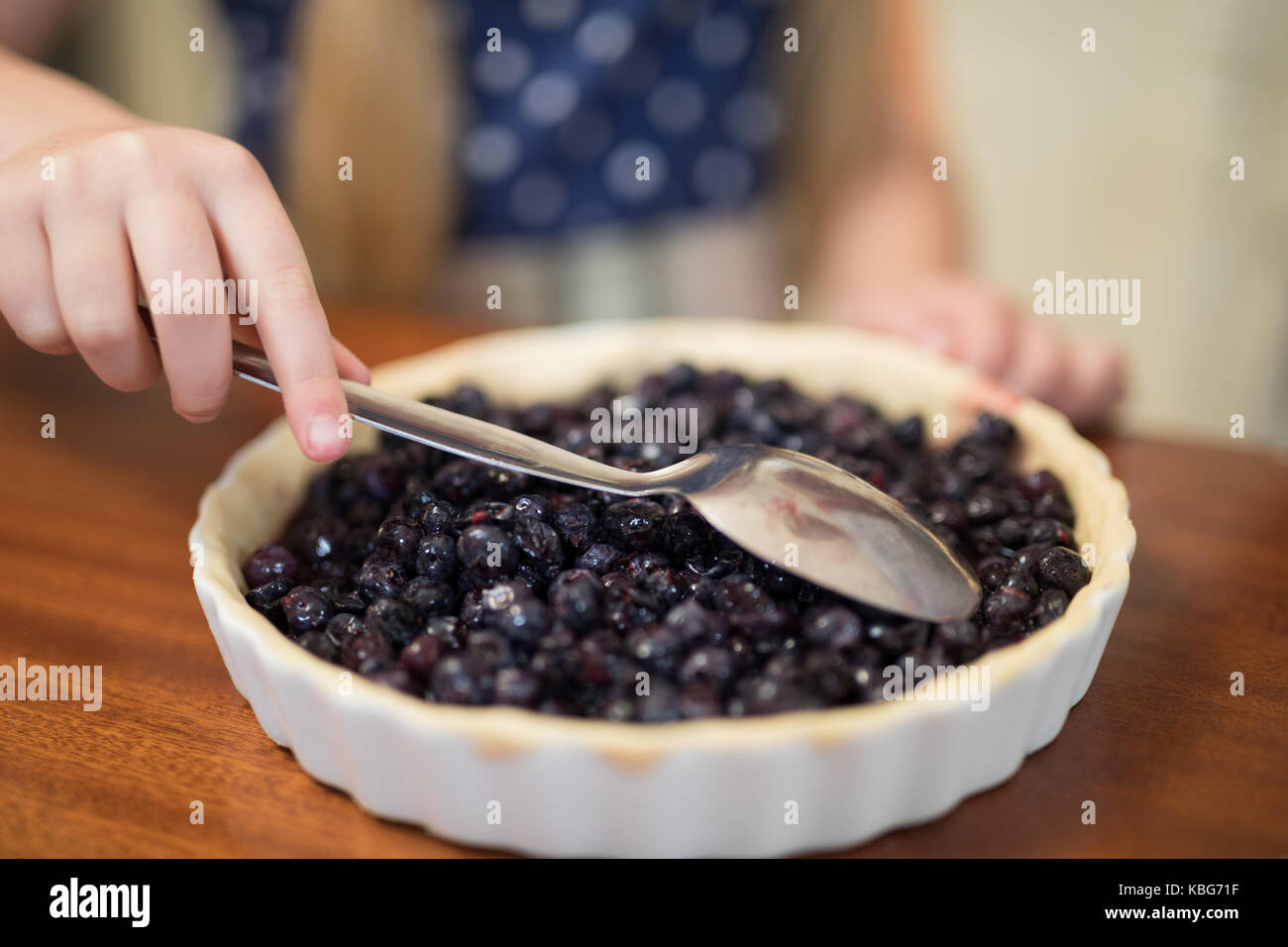 Mid-section of young girl preparing blue berry pie Stock Photo