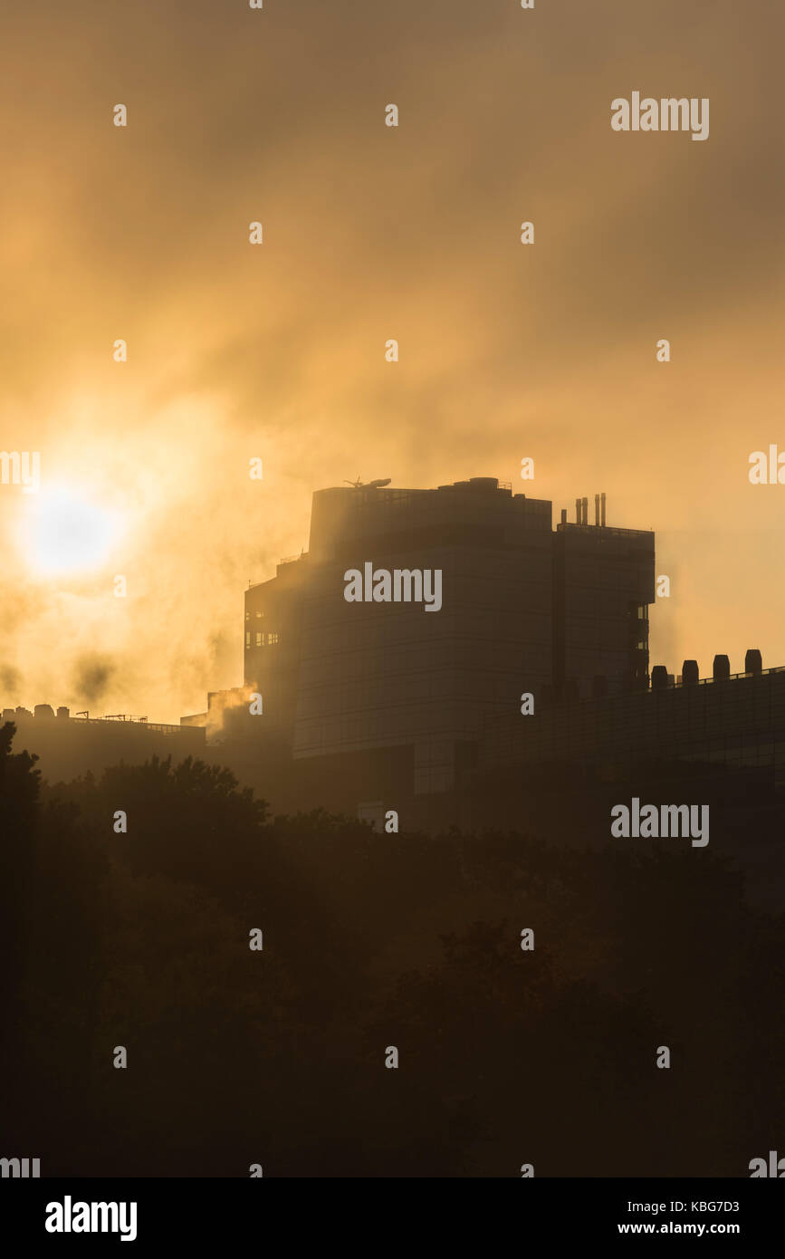 Sun setting over a building on a foggy evening in Boston MA. Stock Photo