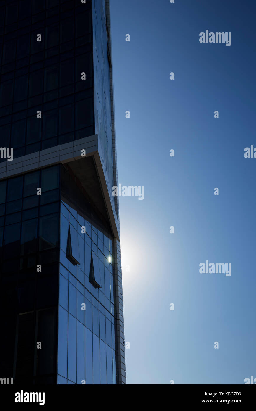 A newly constructed skyscraper against a blue sky and sunrise Stock Photo
