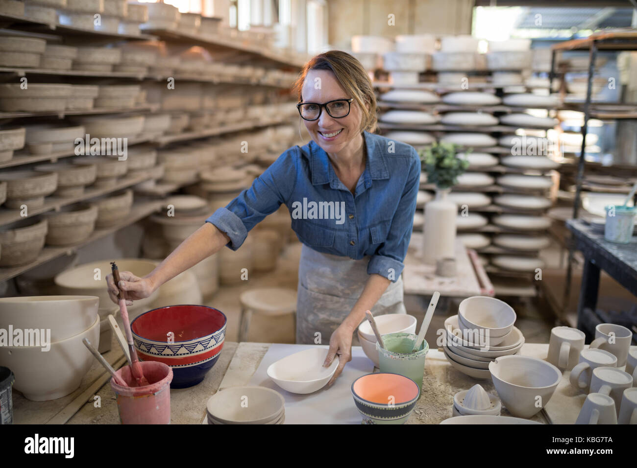 Female potter painting bowl in pottery workshop Stock Photo - Alamy