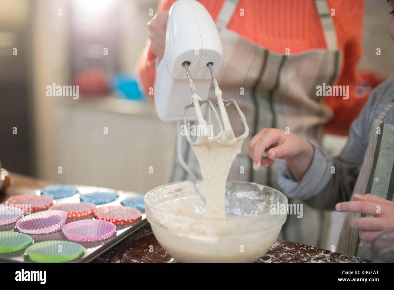 Mid section of mother and daughter mixing eggs and wheat flour in a