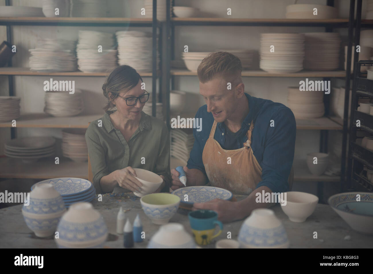 Male and female potter decorating bowl in pottery workshop Stock Photo ...