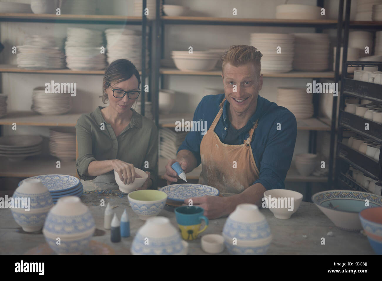 Male and female potter decorating bowl in pottery workshop Stock Photo ...