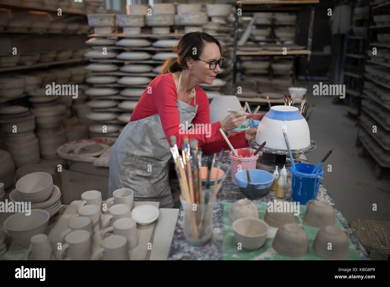 Female potter painting bowl in pottery workshop Stock Photo - Alamy