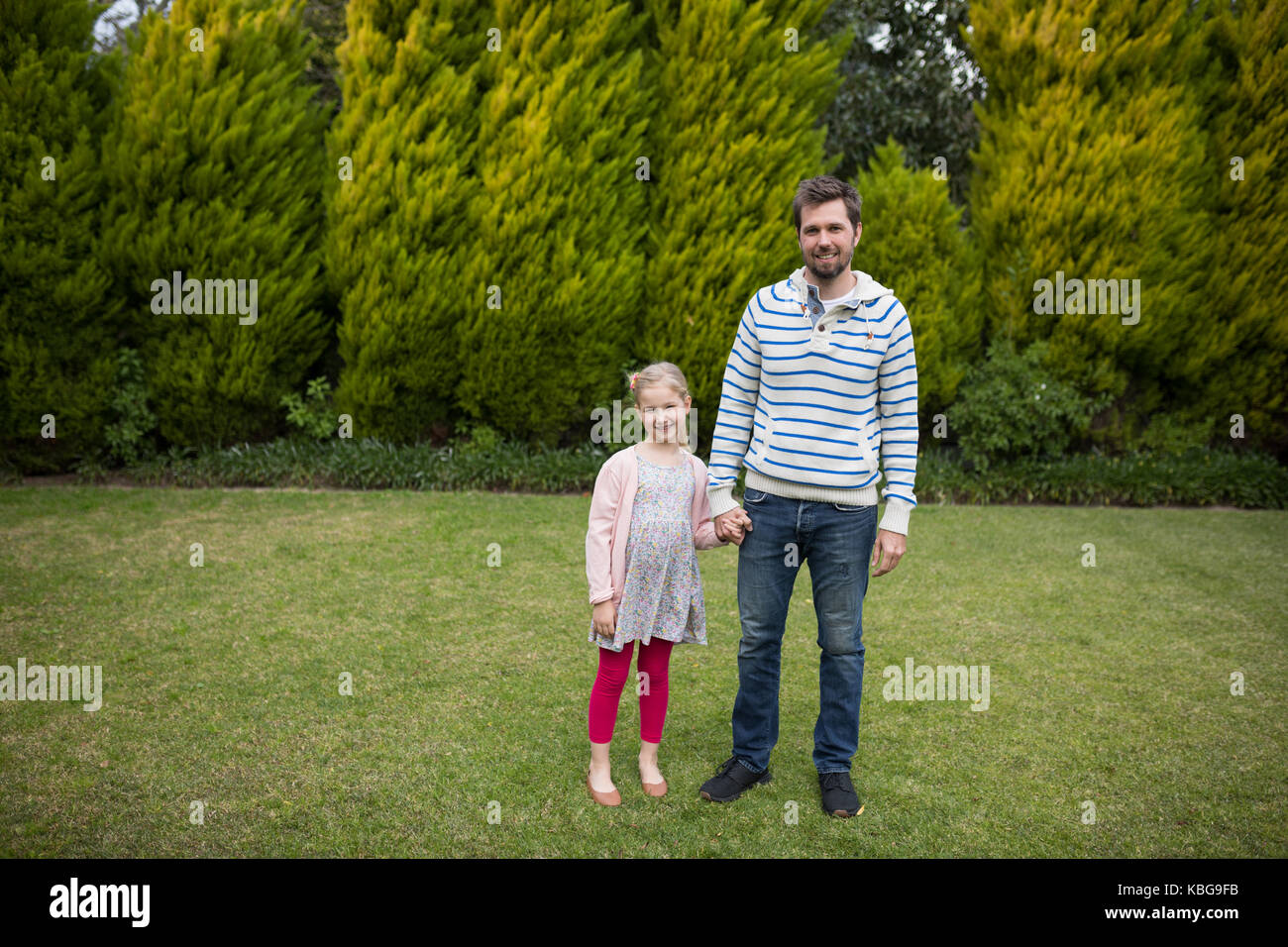 Young girl and father holding hands in the park Stock Photo - Alamy