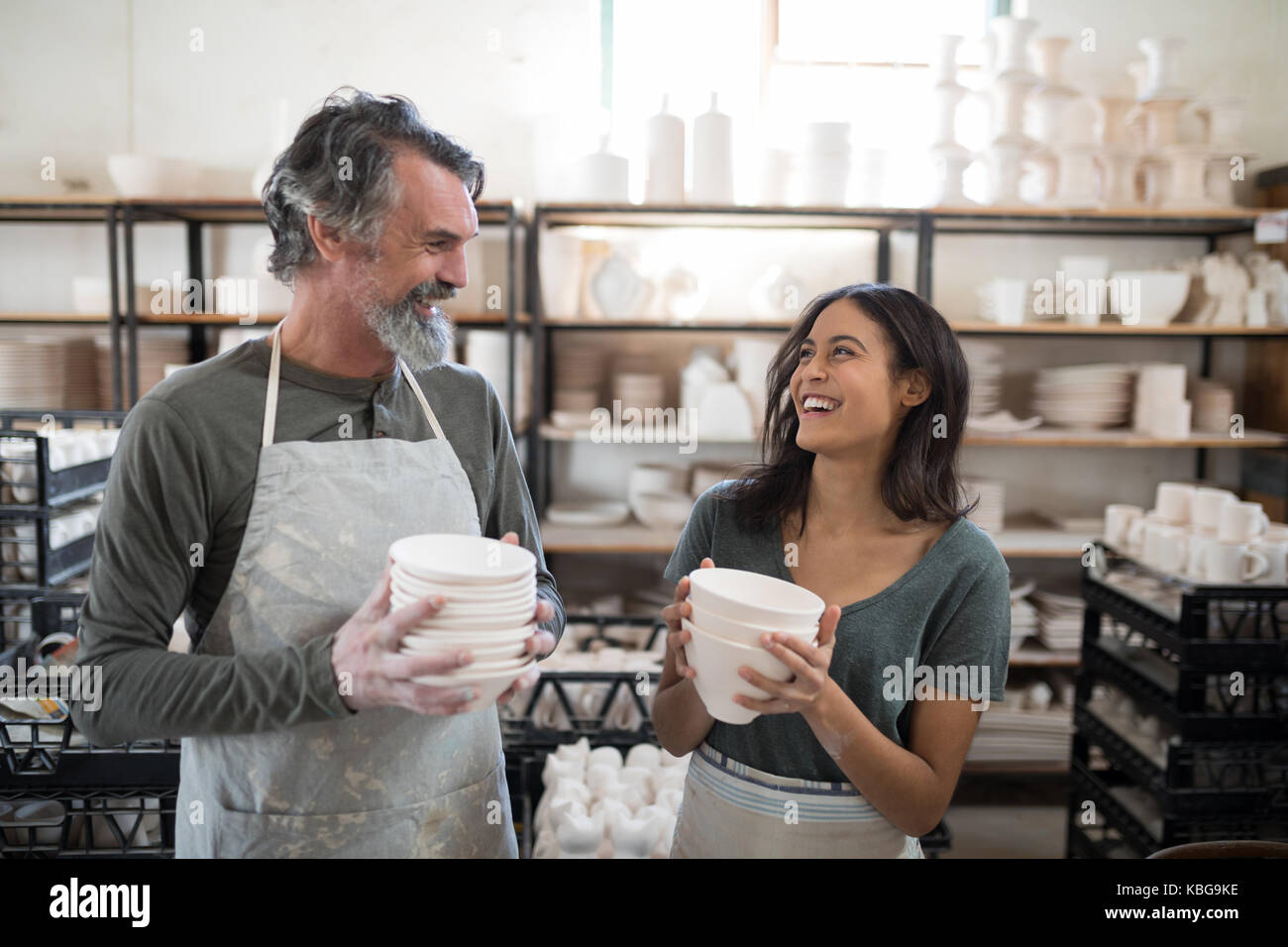 Male and female potter holding ceramic bowls in pottery workshop Stock ...