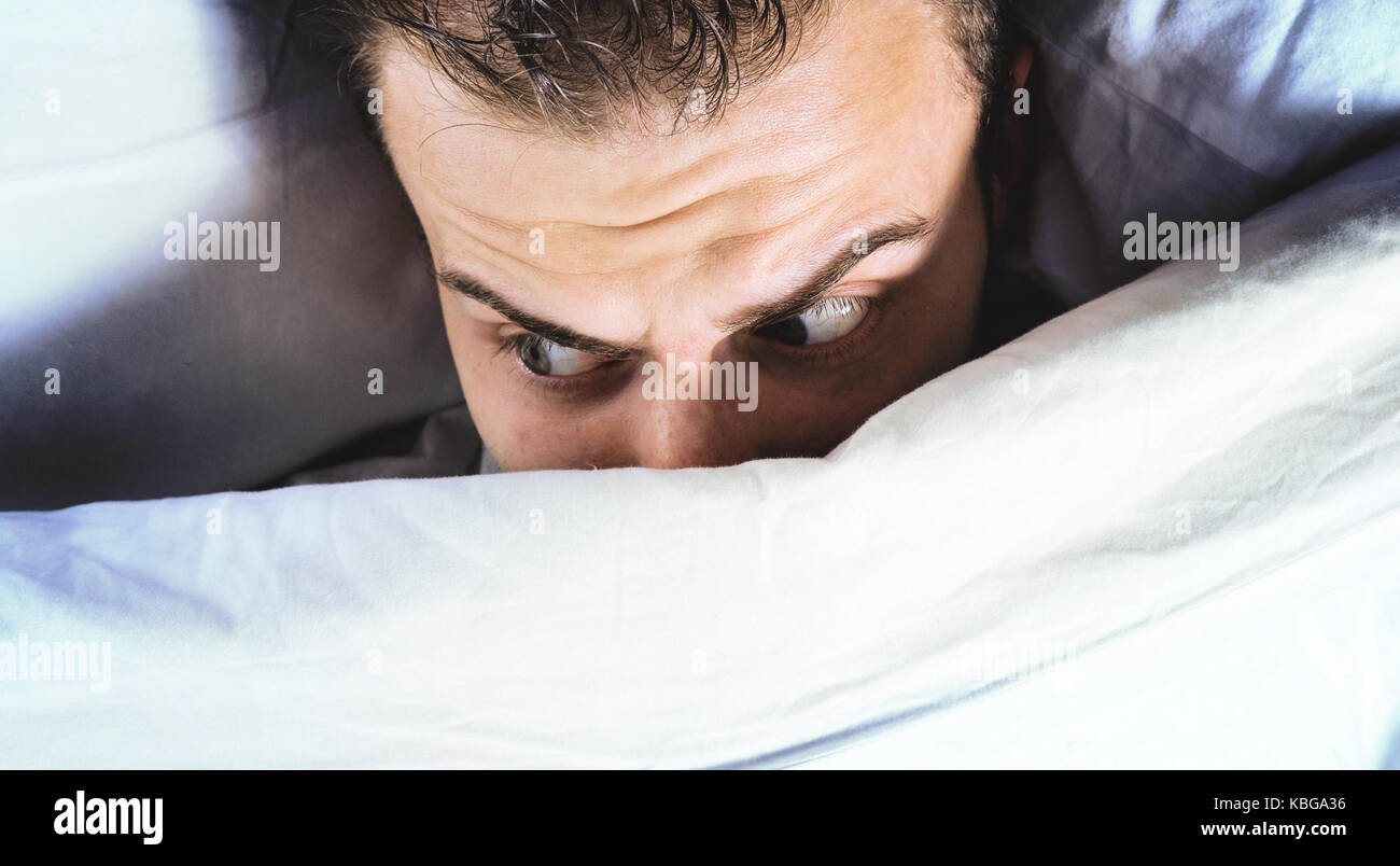 man lies in bed and sees nightmares, can not fall asleep from fear, bad sleep, insomnia Stock Photo