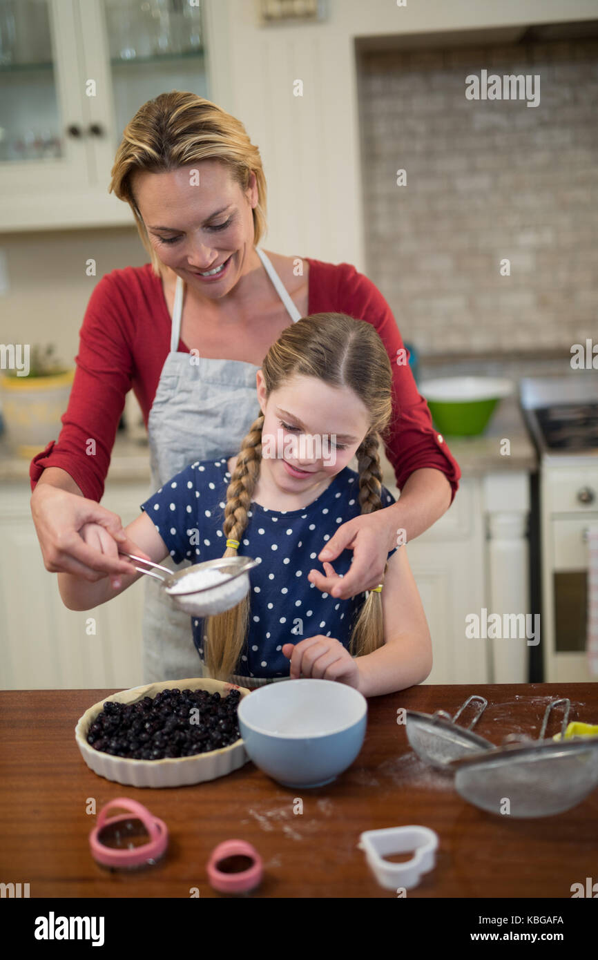Mother and daughter preparing blue berry pie in kitchen Stock Photo