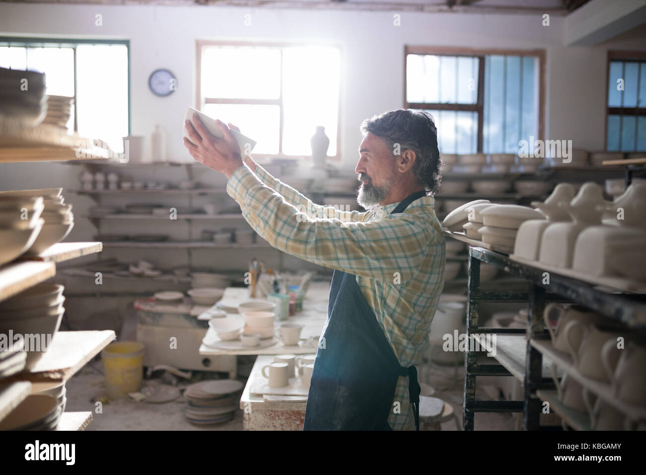 Male potter checking bowl in pottery workshop Stock Photo - Alamy