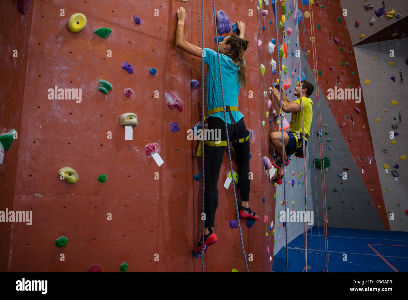 Dedicated athletes climbing wall in heath club Stock Photo
